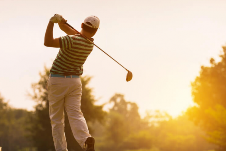 man playing golf at sunset