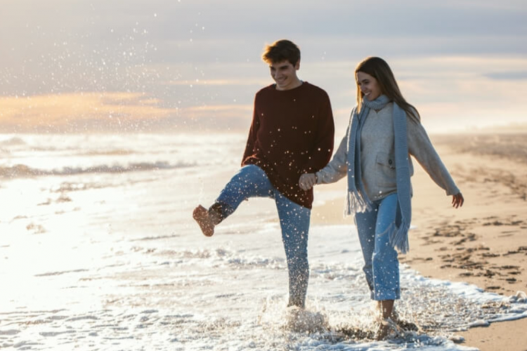 couple walking on the beach during the fall dressed in warm clothing