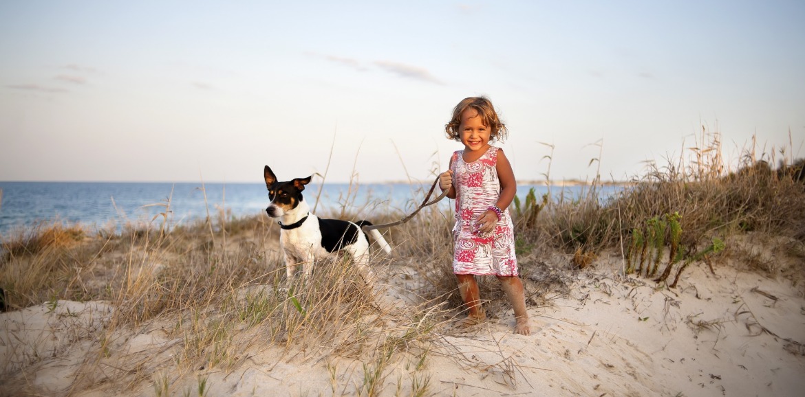 little girl with dog on the beach | Sunset Vacations