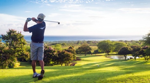 man playing golf near the beach | Sunset Vacations