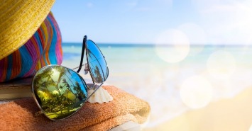 sunglasses and beach accessories sitting on the beach | Sunset Vacations
