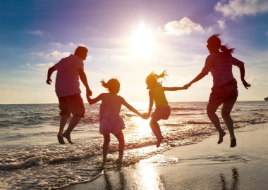 family jumping in the waves together | Sunset Vacations