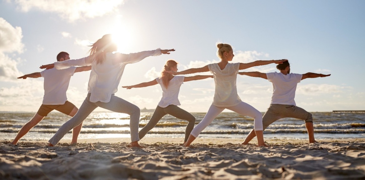 people doing yoga on the beach | Sunset Vacations