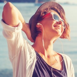 young woman listening to music on the beach | Sunset Vacations